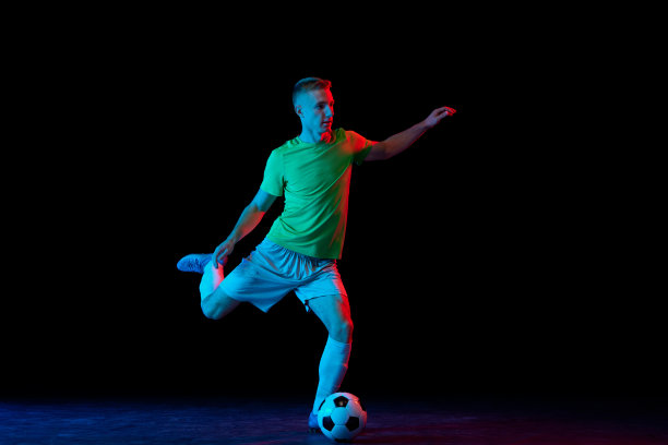 的目标。年轻的足球，足球运动员在运动和行动与球隔离在霓虹灯的黑暗背景。成就，创造力，运动，能量，冠军的概念图片下载