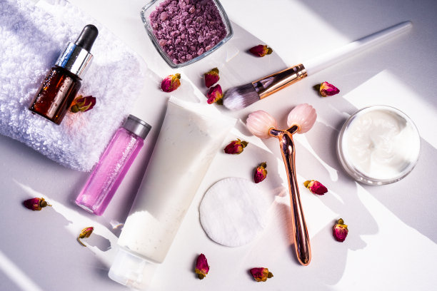 白色底色、美容护理、面部按摩、面霜、面膜、白毛巾。复制的空间。水疗，毛巾，面霜，浴盐，面部按摩器。图片下载