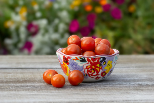 花园里木桌上的碗里装着圣女果。图片下载