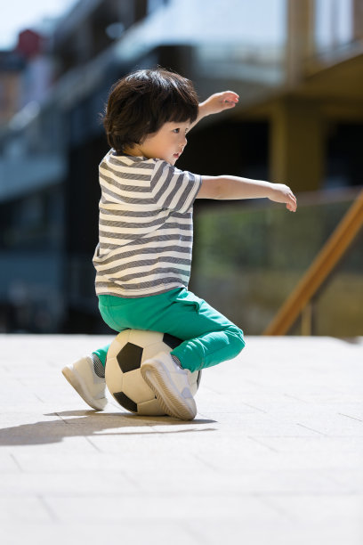 小男孩是一个足球迷，坐在和踢足球-库存照片图片下载