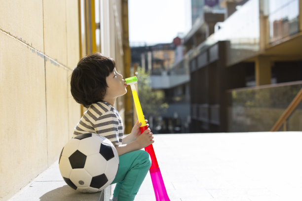 小男孩叫喊着，吹着欢呼的号角作为一个足球迷-股票照片图片下载