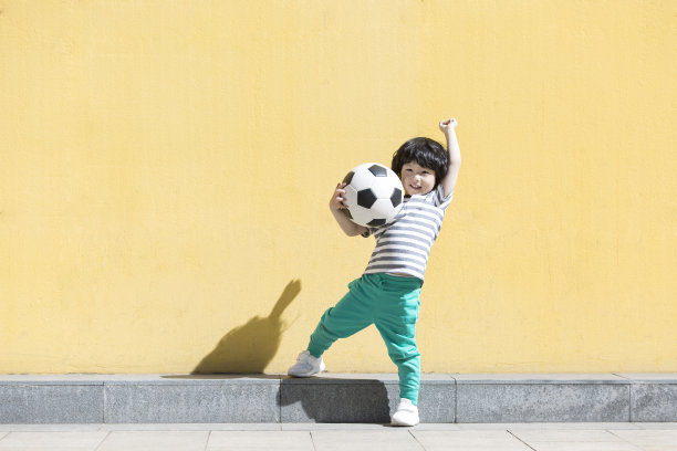 一个对足球充满热情的球迷男孩，拿着足球，玩着超级英雄的股票照片图片下载