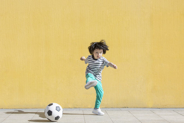 小男孩是一个足球球迷，正在踢足球-库存照片图片下载