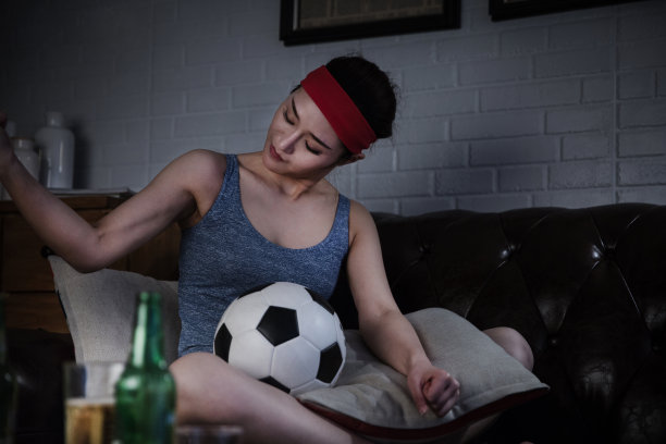 深夜坐在客厅沙发上看电视上的足球比赛的女士带着兴奋的表情——库存照片图片下载