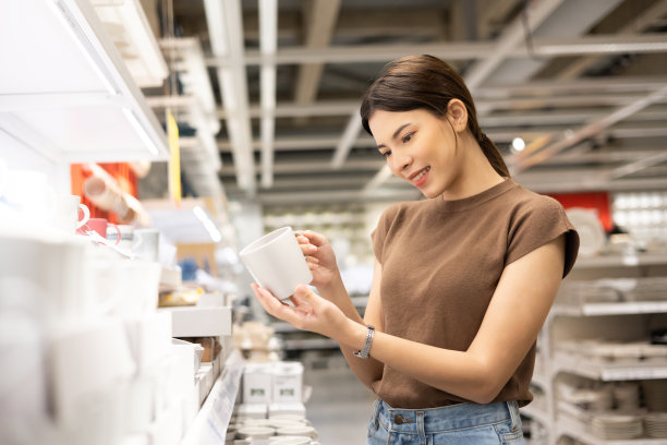 家庭主妇为她的房子买盘子、碗和一杯水。年轻女子在陶瓷商店市场大厅为食品容器挑选新项目家庭配件和家庭产品图片下载