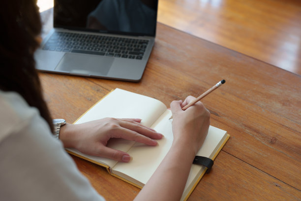 一名亚洲少女在图书馆的木桌上使用电脑和笔记本通过视频会议在线学习图片下载