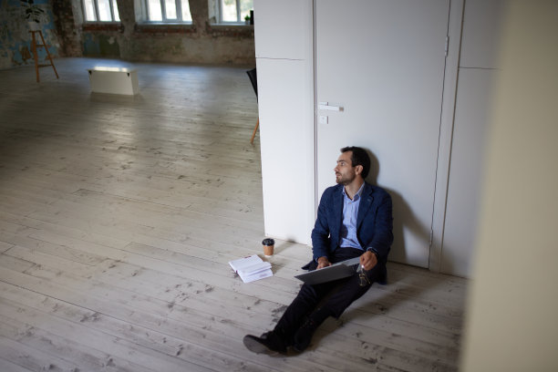 年轻商人的画像坐在空房间的地板上。业务开放。从事公司的新项目图片下载