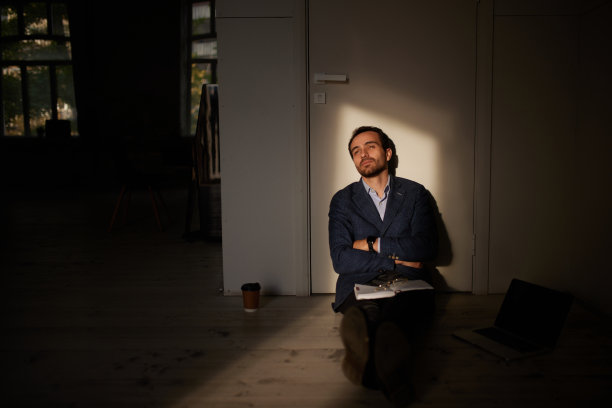 年轻商人的画像坐在空房间的地板上。业务关闭。萧条和危机。事业的失败图片下载