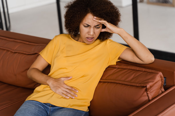 胃疼。生病的非裔美国女孩捂着腹部，因为它很疼。胰腺炎胰腺疾病发炎。图片下载