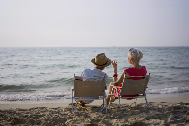 老夫妇坐在沙滩上聊天。图片下载