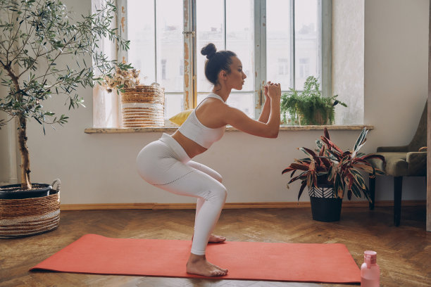 自信的女子站在蹲的姿势，在家里的窗前练习图片下载