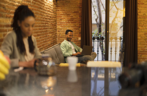 留着非洲发型的帅哥在家里用笔记本电脑图片下载