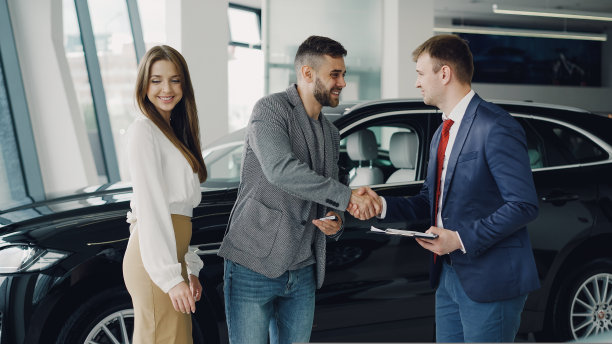 年轻的大胡子男子为他迷人的妻子买车，与经理握手并领取钥匙图片下载