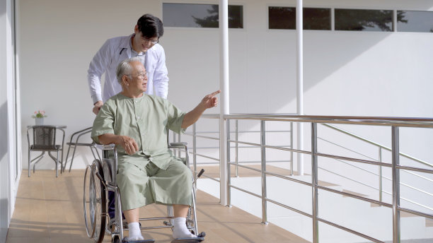 医生带着老年病人在公园里散步。图片下载