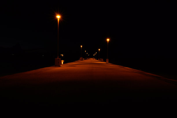 在漆黑的夜空下，被室外灯光照亮的小路图片下载