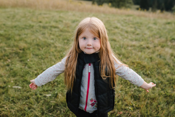 孩子在秋天的山上。女孩在草地上奔跑，享受大自然。小徒步旅行者走在雾蒙蒙的山顶上。世界旅游日。积极的户外游戏。特写镜头。图片下载