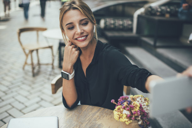 快乐的千禧一代音乐爱好者戴着耳机听音频，在闲暇时间使用现代手机工具点击自拍照片，漂亮的潮女孩一边写博客一边拍视频视频日志图片下载