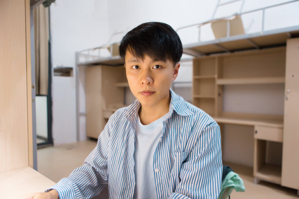 一个大学生在宿舍里的肖像，看着相机图片下载
