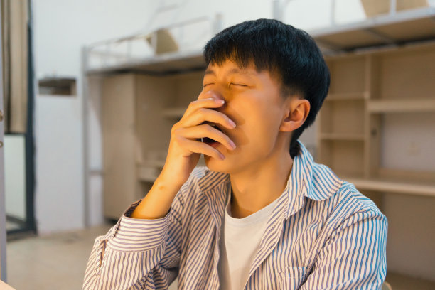 一个大学生在长时间学习后，晚上打了个哈欠图片下载