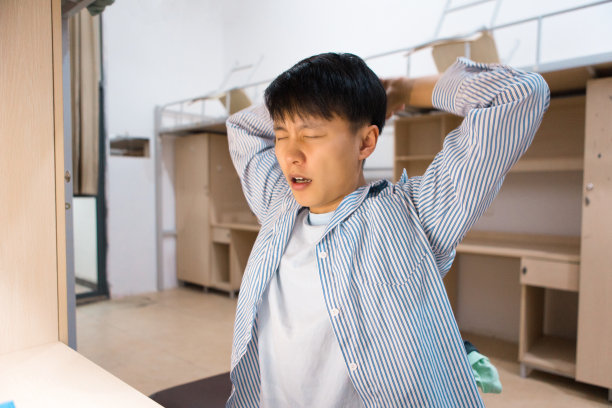 一个大学生在长时间学习后，晚上打了个哈欠图片下载