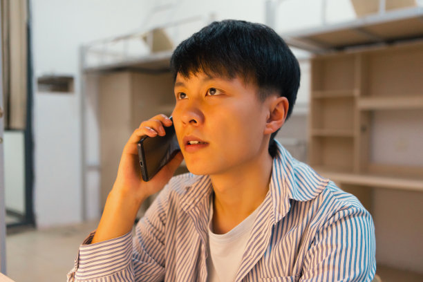 一个大学生正在宿舍里用手机放音乐，看书图片下载