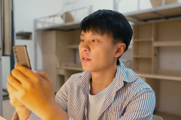 一个大学生正在宿舍里用手机放音乐，看书图片下载