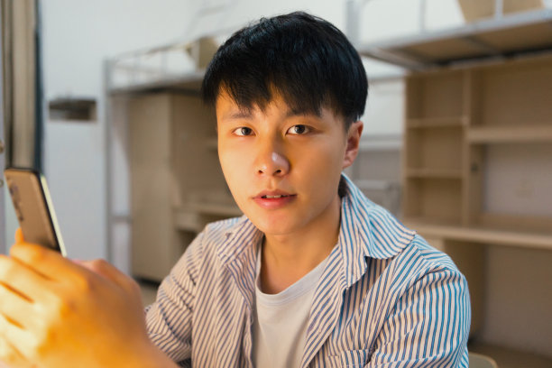 一个大学生在宿舍里的肖像，看着相机图片下载