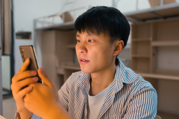 一个大学生正在宿舍里用手机放音乐，看书图片下载