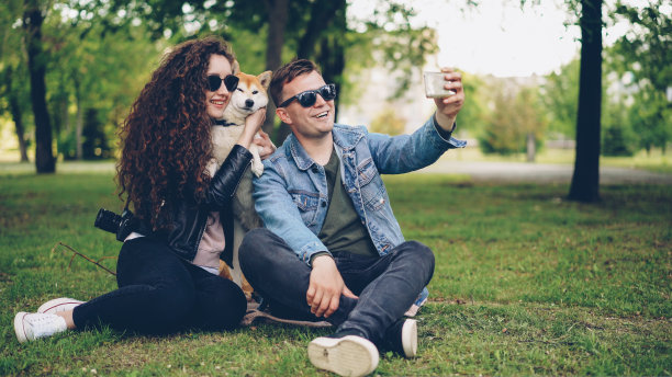 著名博主正在录制他、他的妻子和可爱的狗的视频，男子拿着智能手机，边说边看镜头，然后拍女人和动物。图片下载