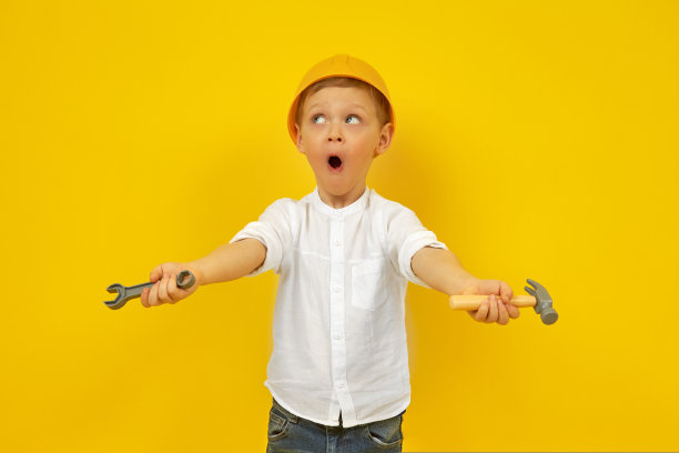 一个戴着安全帽的可爱男孩，手里拿着扳手和锤子图片下载