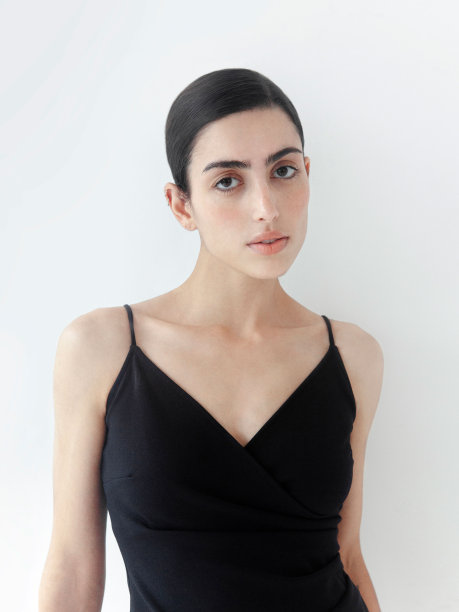 美丽的褐发女子穿着优雅的黑色连衣裙时装模特工作室肖像在光背景特写肖像图片下载