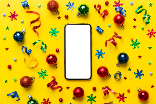 圣诞节网上购物从家里的电话与空白白色显示顶视图。智能手机与复制空间彩色背景与圣诞装饰球，。寒假销售背景图片下载