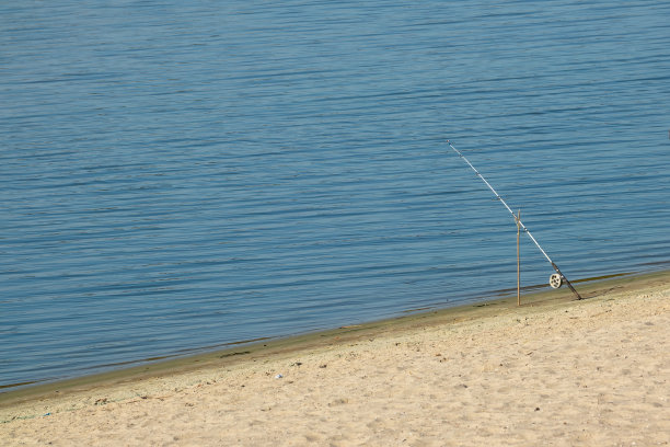 在阳光明媚的日子里，在河流或湖泊的沙滩上钓鱼图片下载