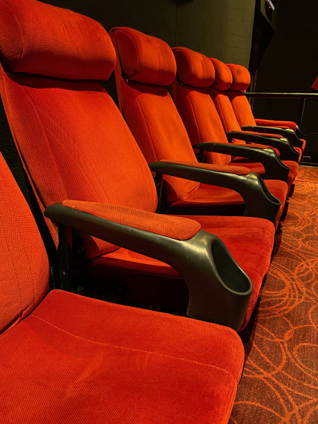 图像排天鹅绒电影院座位，空分层红色座椅与饮料持有人，电影院座位，侧面视图，重点在前景图片下载
