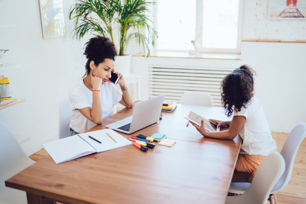 年轻的自由职业母亲坐在家里和小女孩打电话图片下载