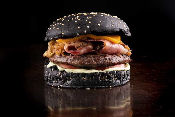 油腻有趣的万圣节主题汉堡脆黑面包培根和洋葱片与芝麻在木桌上孤立图片下载