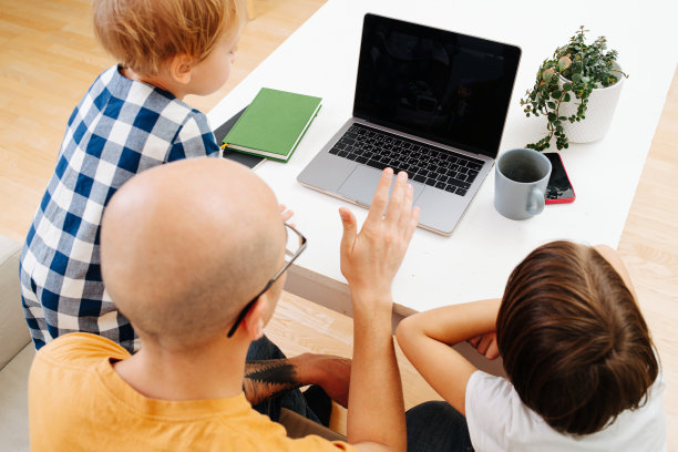 孩子们看着他们的父亲在笔记本电脑上工作图片下载