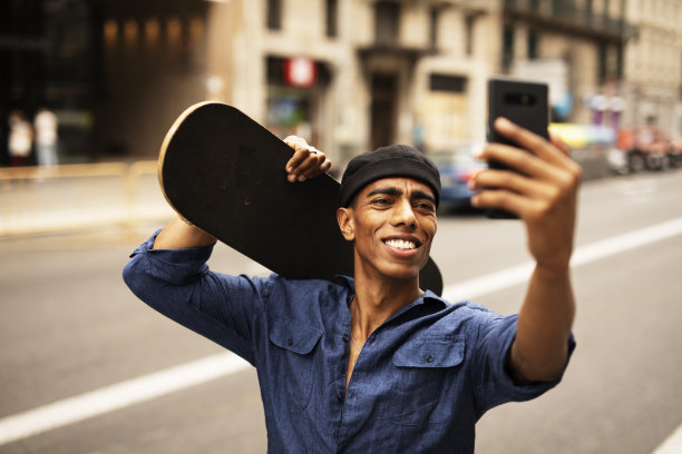 年轻英俊的男子与滑板。图片下载