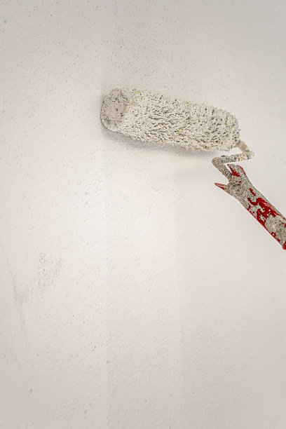 红色长柄上的白色滚筒在墙上作画图片下载