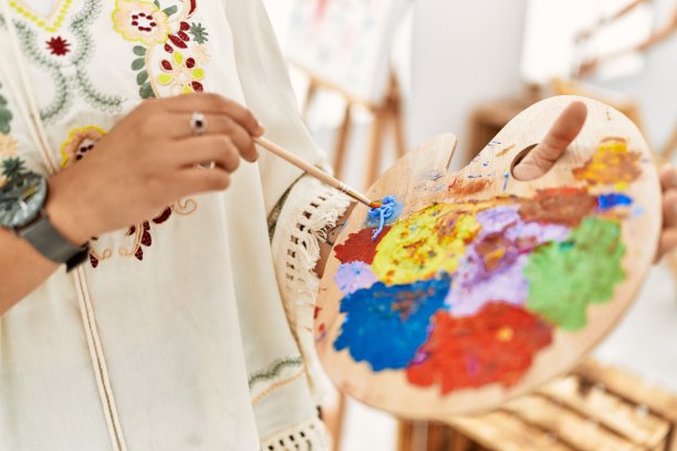 年轻的西班牙妇女在艺术工作室调色板上混合颜色图片下载