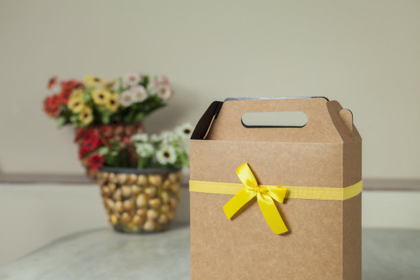 礼物包装与黄色的蝴蝶结和鲜花为背景。图片下载