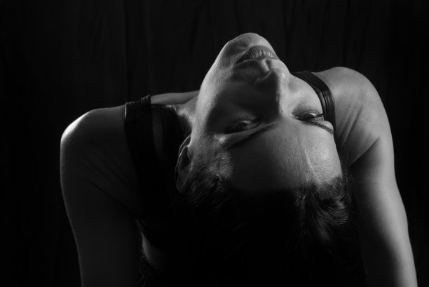 工作室肖像的年轻女子在黑色t恤对纯黑色的工作室背景。图片下载