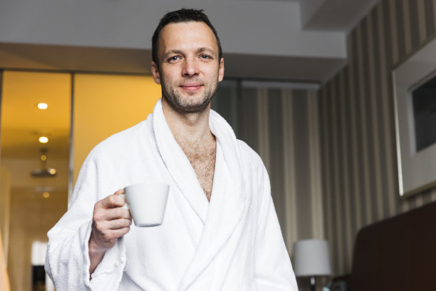 微笑的年轻白人男子在白色的棉浴袍图片下载