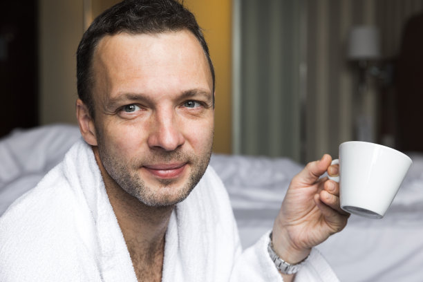 画像微笑的年轻男子在白色的棉浴袍图片下载