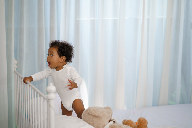 快乐的非裔美国小男孩爬上床头，寻找一些东西来学习图片下载