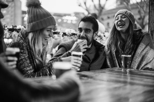 年轻人有乐趣喝啤酒在酒吧餐厅-软焦点对右女孩的脸-黑白编辑图片下载
