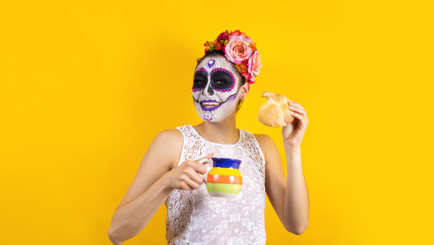 在拉丁美洲的墨西哥，卡特里娜妇女手持传统的墨西哥hojaldra面包，庆祝亡灵节或万圣节派对图片下载