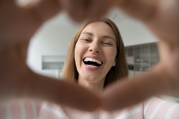 幸福的女人展示着爱的象征，微笑着凝视着镜头图片下载