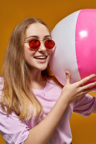 拿着沙滩球看向远方的白人少女图片下载