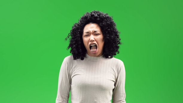 年轻的黑人女性，卷曲的爆炸头和厌恶的表情在绿色的屏幕背景图片下载